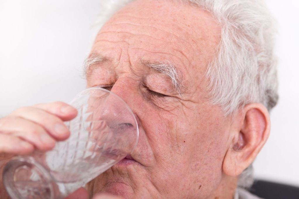anziano beve acqua per idratarsi
